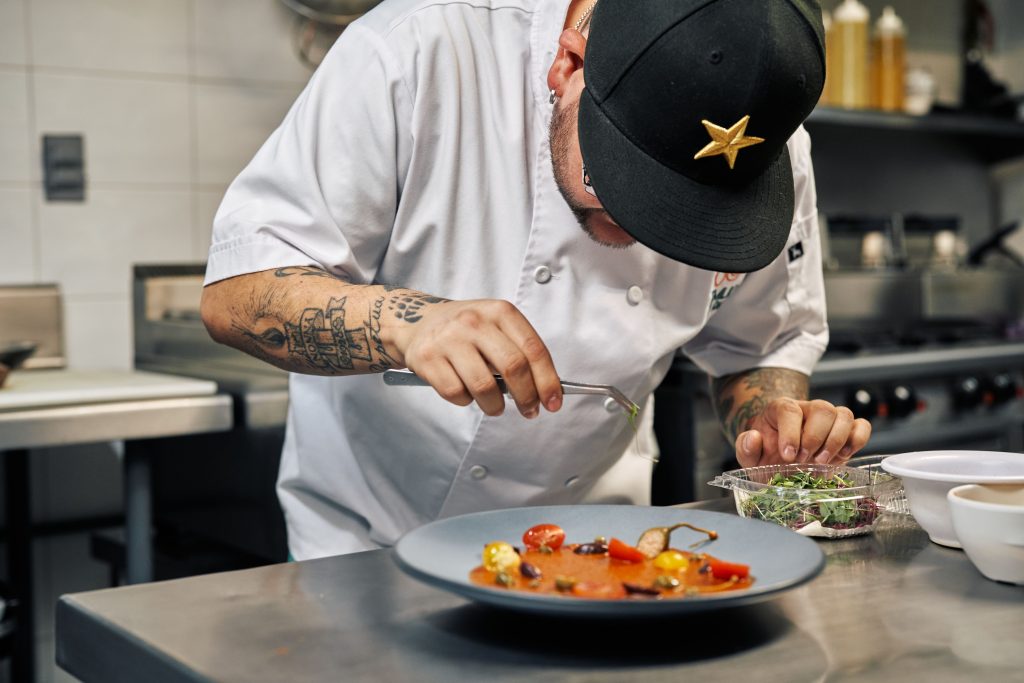 Séf precízen díszíti a gourmet fogást egy főzőversenyen